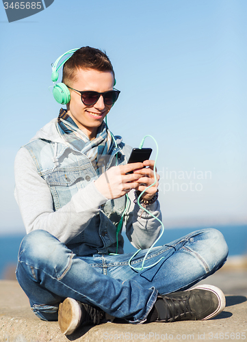 Image of happy young man in headphones with smartphone