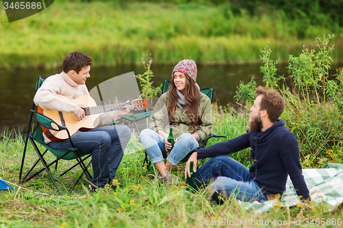 Image of group of tourists playing guitar in camping