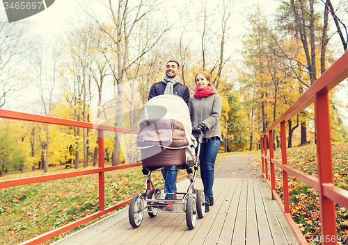 Image of smiling couple with baby pram in autumn park