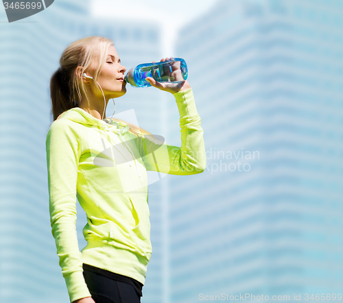 Image of woman drinking water after doing sports outdoors
