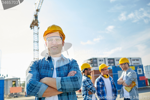 Image of group of smiling builders in hardhats outdoors