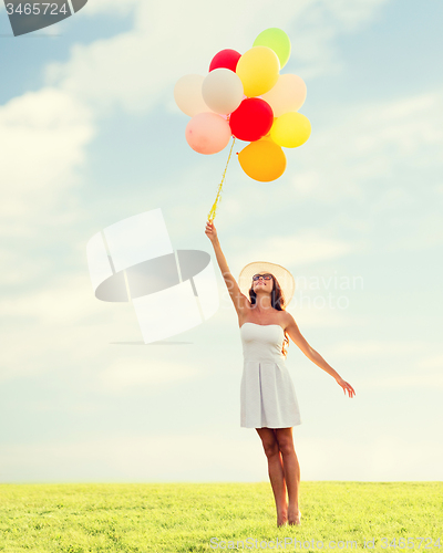 Image of smiling young woman in sunglasses with balloons