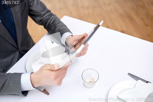 Image of close up of man with tablet pc at restaurant