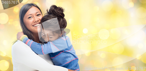 Image of happy mother and daughter hugging over lights