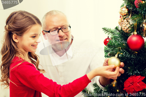 Image of smiling family decorating christmas tree at home