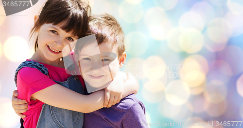 Image of two happy kids hugging over blue lights background