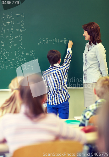 Image of teacher and schoolboy writing on chalk board