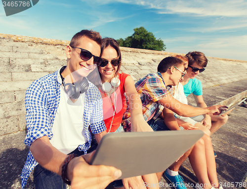 Image of group of smiling friends with tablet pc outdoors