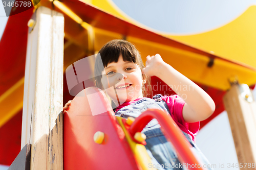 Image of happy little girl climbing on children playground