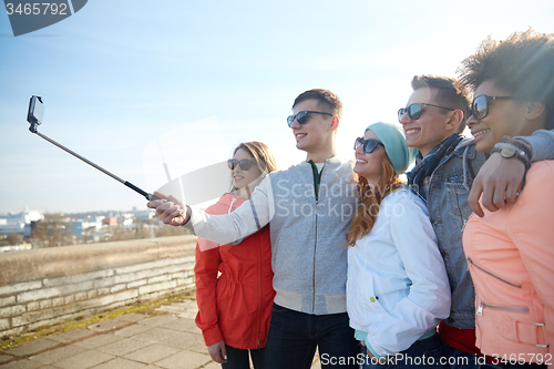 Image of smiling friends taking selfie with smartphone