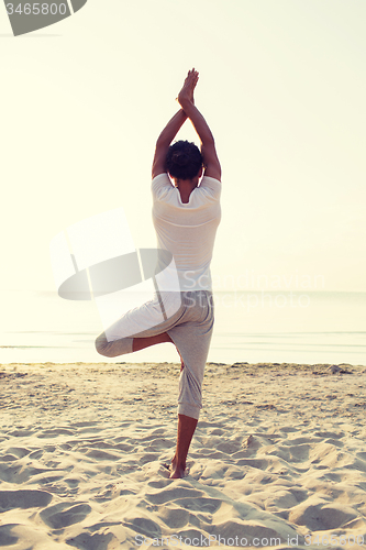 Image of man making yoga exercises outdoors from back