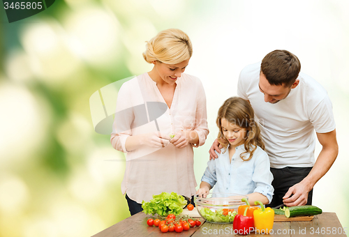 Image of happy family cooking vegetable salad for dinner