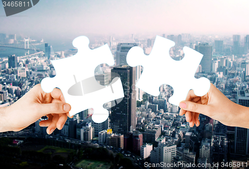 Image of hands with green puzzle over city background