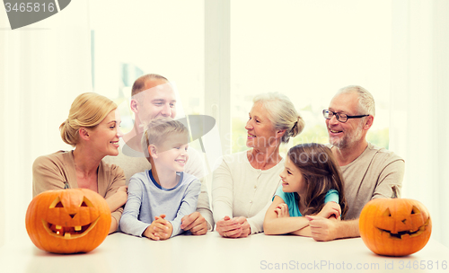 Image of happy family sitting with pumpkins at home