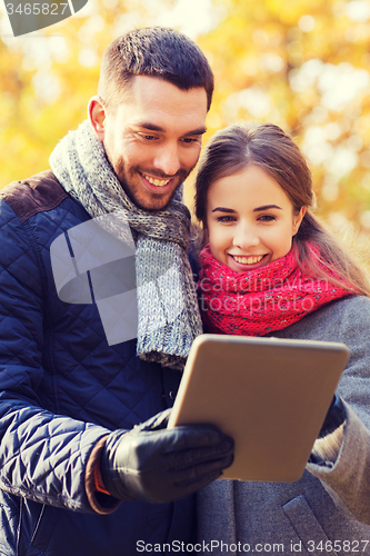 Image of smiling couple with tablet pc in autumn park