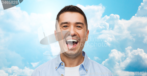Image of laughing man over blue sky and clouds background