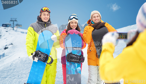 Image of happy friends with snowboards and smartphone