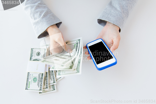 Image of close up of woman hands with smartphone and money