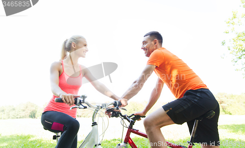 Image of happy couple riding bicycle outdoors
