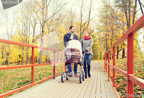 Image of smiling couple with baby pram in autumn park