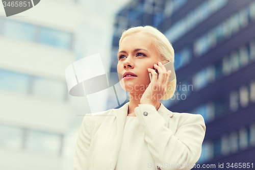 Image of serious businesswoman with smartphone outdoors