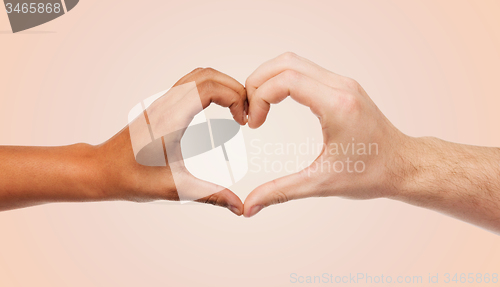 Image of woman and man hands showing heart shape