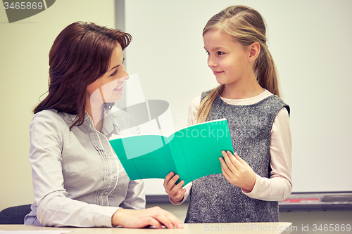 Image of school girl with notebook and teacher in classroom