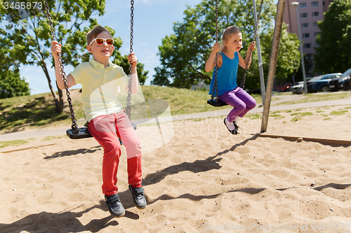 Image of two happy kids swinging on swing at playground