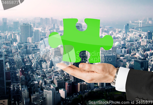 Image of close up of man holding green puzzle piece