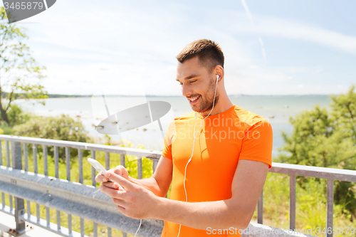 Image of smiling young man with smartphone and earphones