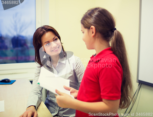 Image of school girl with notebook and teacher in classroom