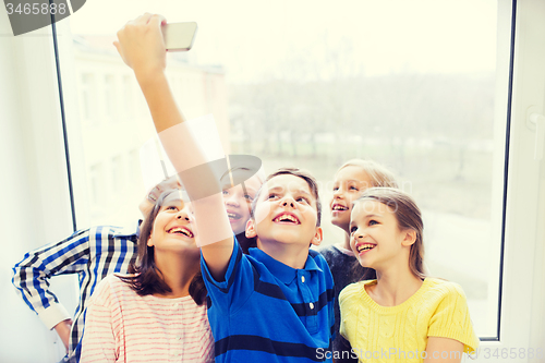 Image of group of school kids taking selfie with smartphone