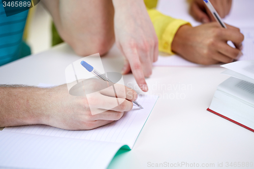 Image of close up of students hands writing to notebooks