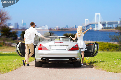 Image of happy man and woman near cabriolet car in tokyo