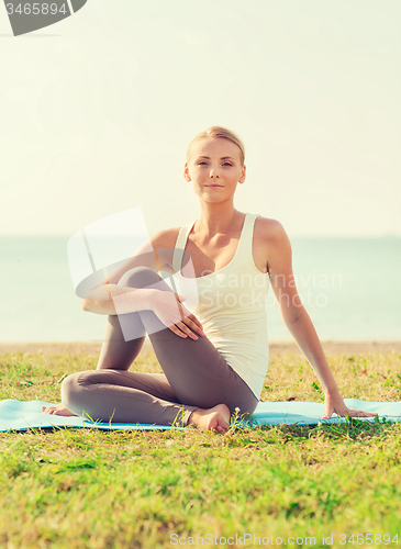 Image of young woman making yoga exercises outdoors