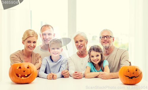 Image of happy family sitting with pumpkins at home