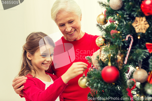 Image of smiling family decorating christmas tree at home