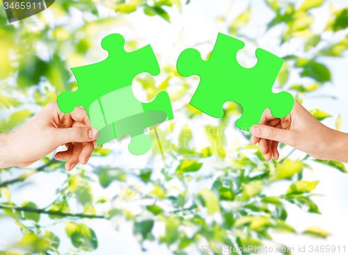 Image of hands with green puzzle over natural background