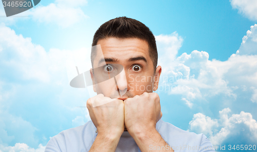 Image of scared man over blue sky and clouds background