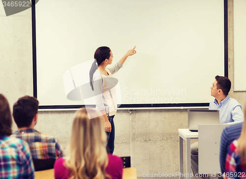 Image of group of students and smiling teacher in classroom