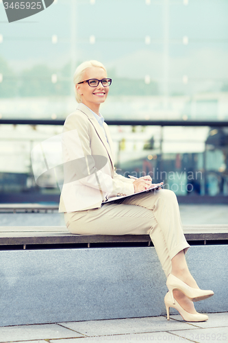 Image of young smiling businesswoman with notepad outdoors