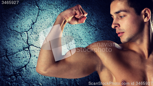 Image of close up of young man flexing and showing biceps