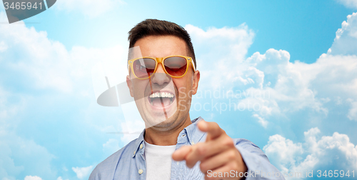 Image of face of laughing man in sunglasses pointing to you