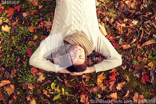 Image of smiling young man lying on ground in autumn park