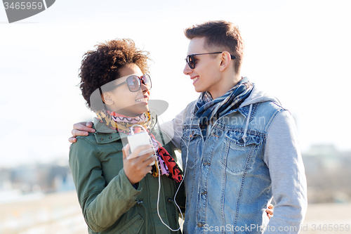 Image of smiling couple with smartphone and earphones
