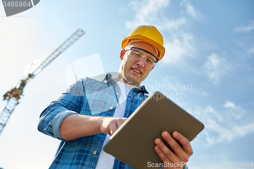 Image of builder in hardhat with tablet pc at construction