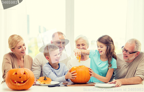 Image of happy family sitting with pumpkins at home