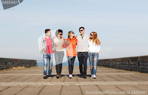 Image of happy teenage friends walking along city street