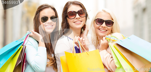 Image of three smiling girls with shopping bags in city