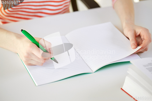 Image of close up of female hands writing to notebook